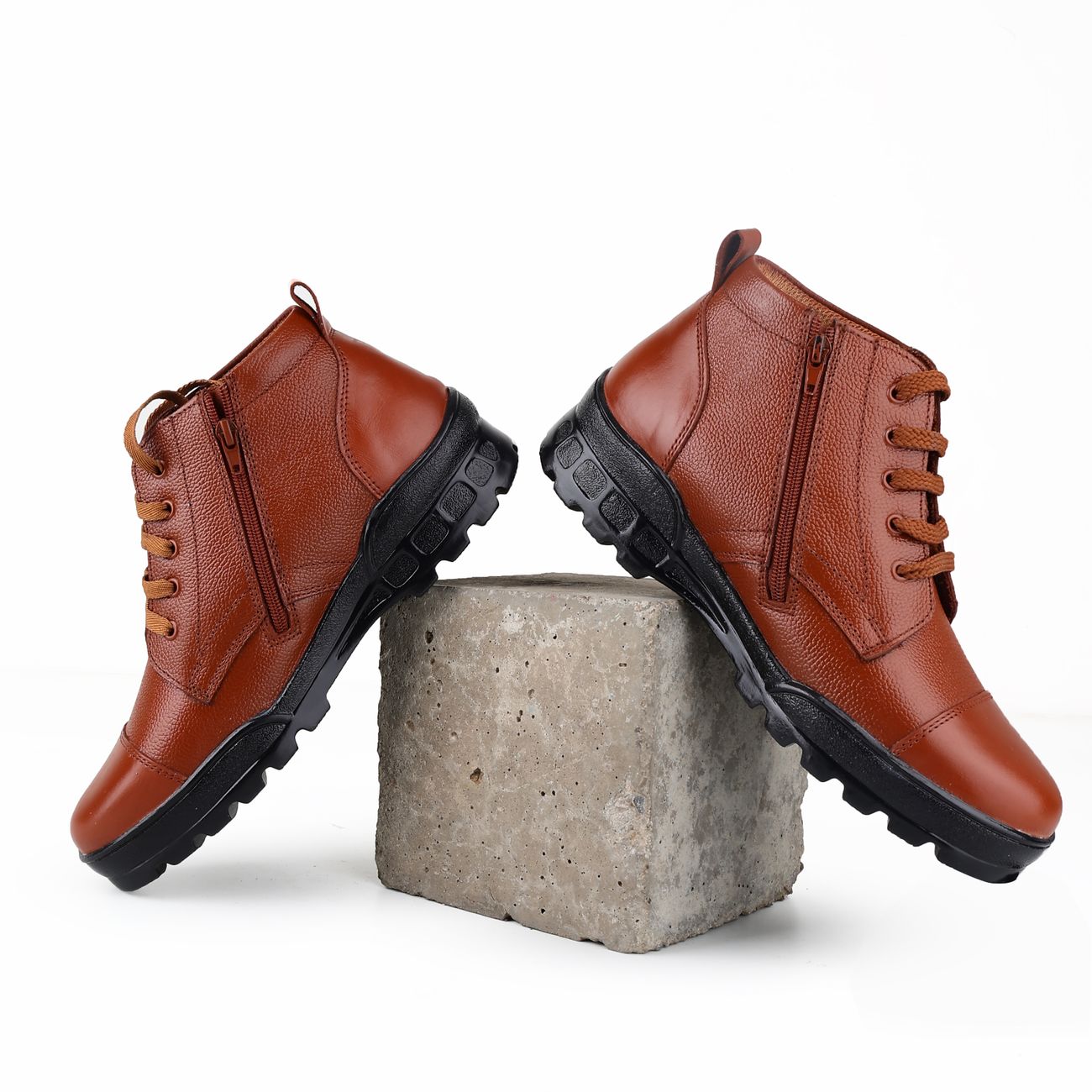 Modern brown leather boots showcased artistically on a concrete block.
