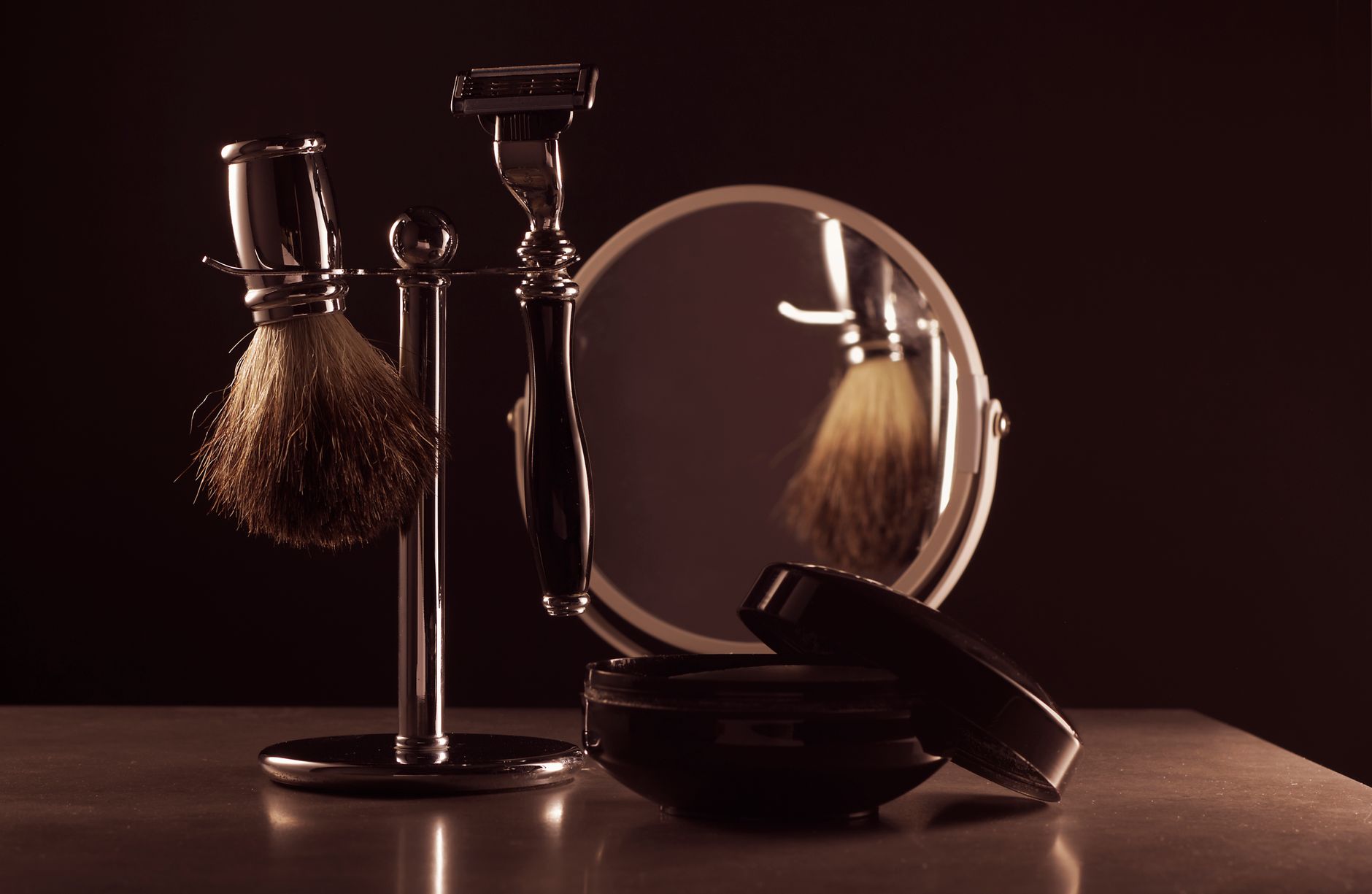 Stylish shaving set featuring a brush, razor, and mirror on a table, ideal for men's grooming.