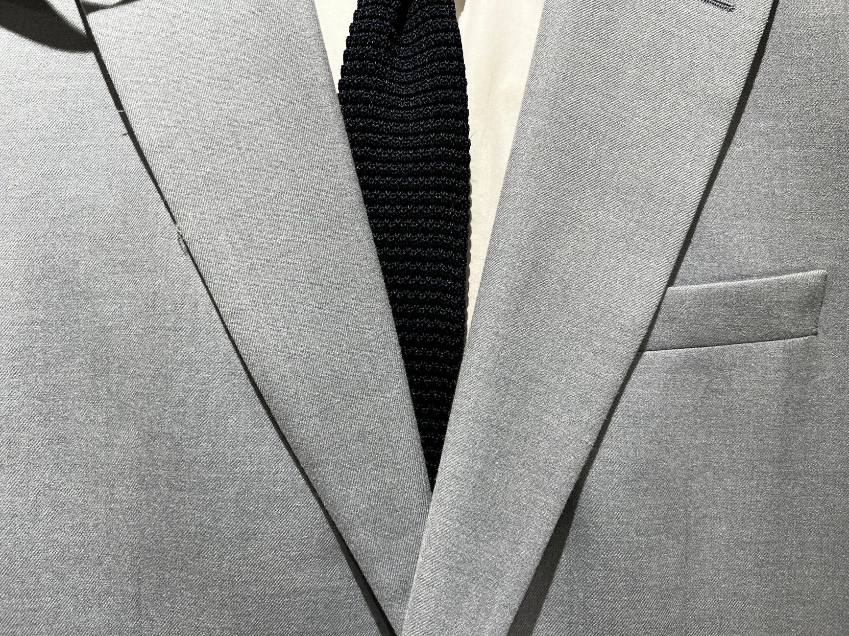 A sophisticated gray suit jacket and black tie combination showcasing formal fashion elegance.