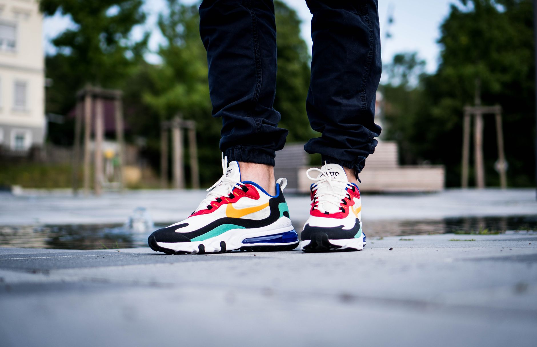 Close-up of colorful Nike sneakers worn outdoors on a stone pavement.