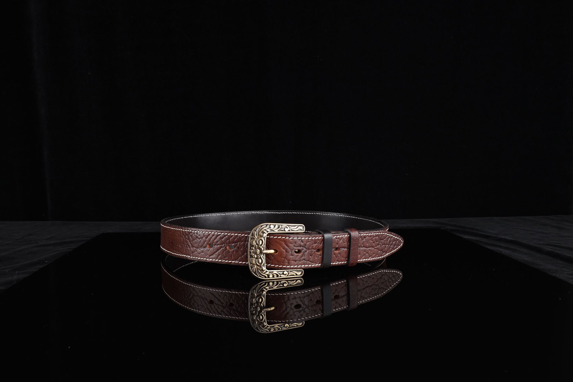 Sophisticated brown leather belt with an ornate metal buckle, perfect for fashion enthusiasts.