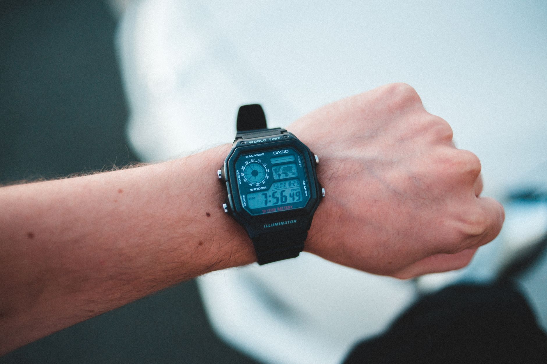 Crop anonymous male showing modern wristwatch with display and numbers on slim hand in soft focus