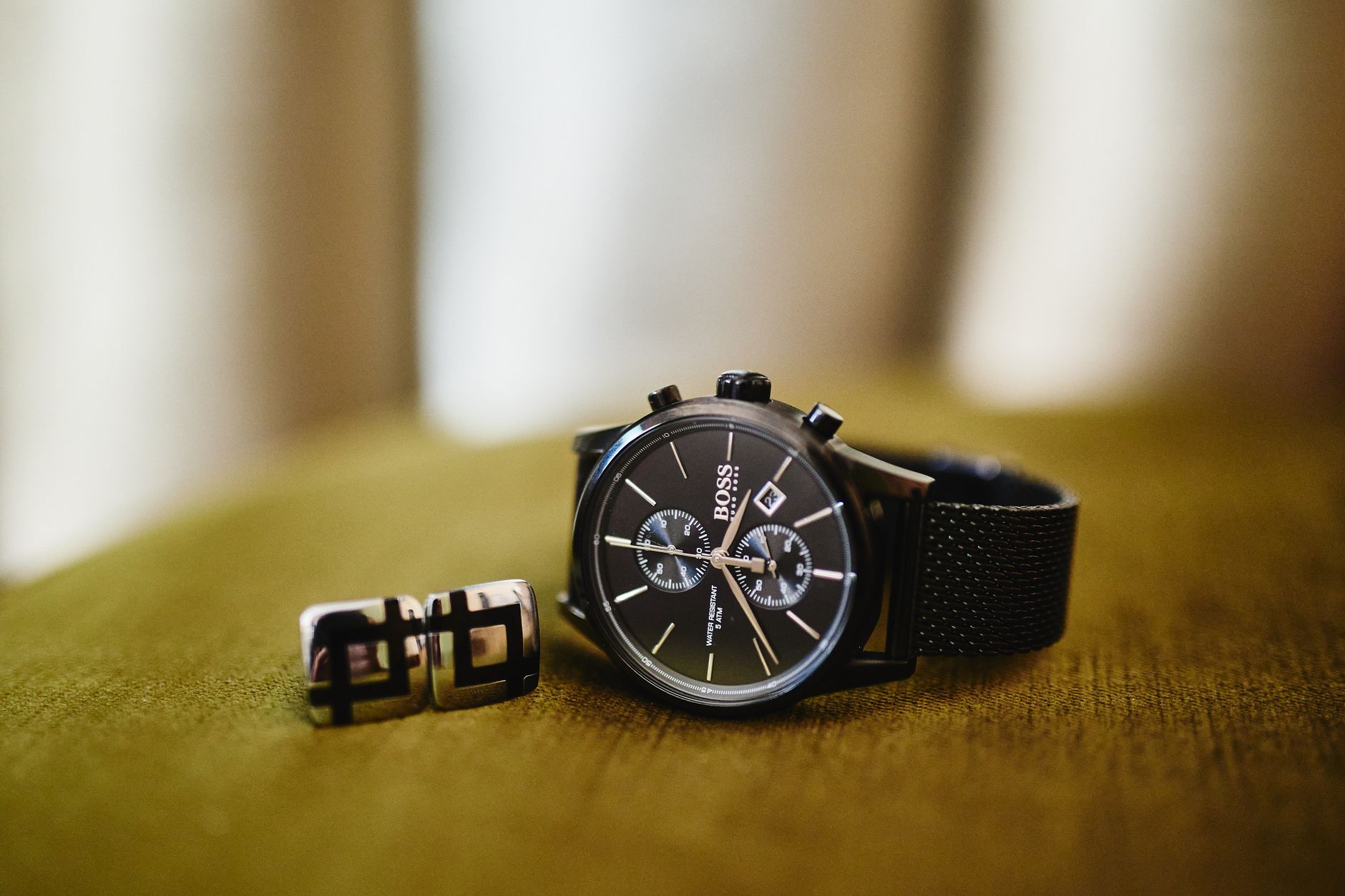 Close-up of a sophisticated black wristwatch paired with stylish cufflinks on a soft surface.