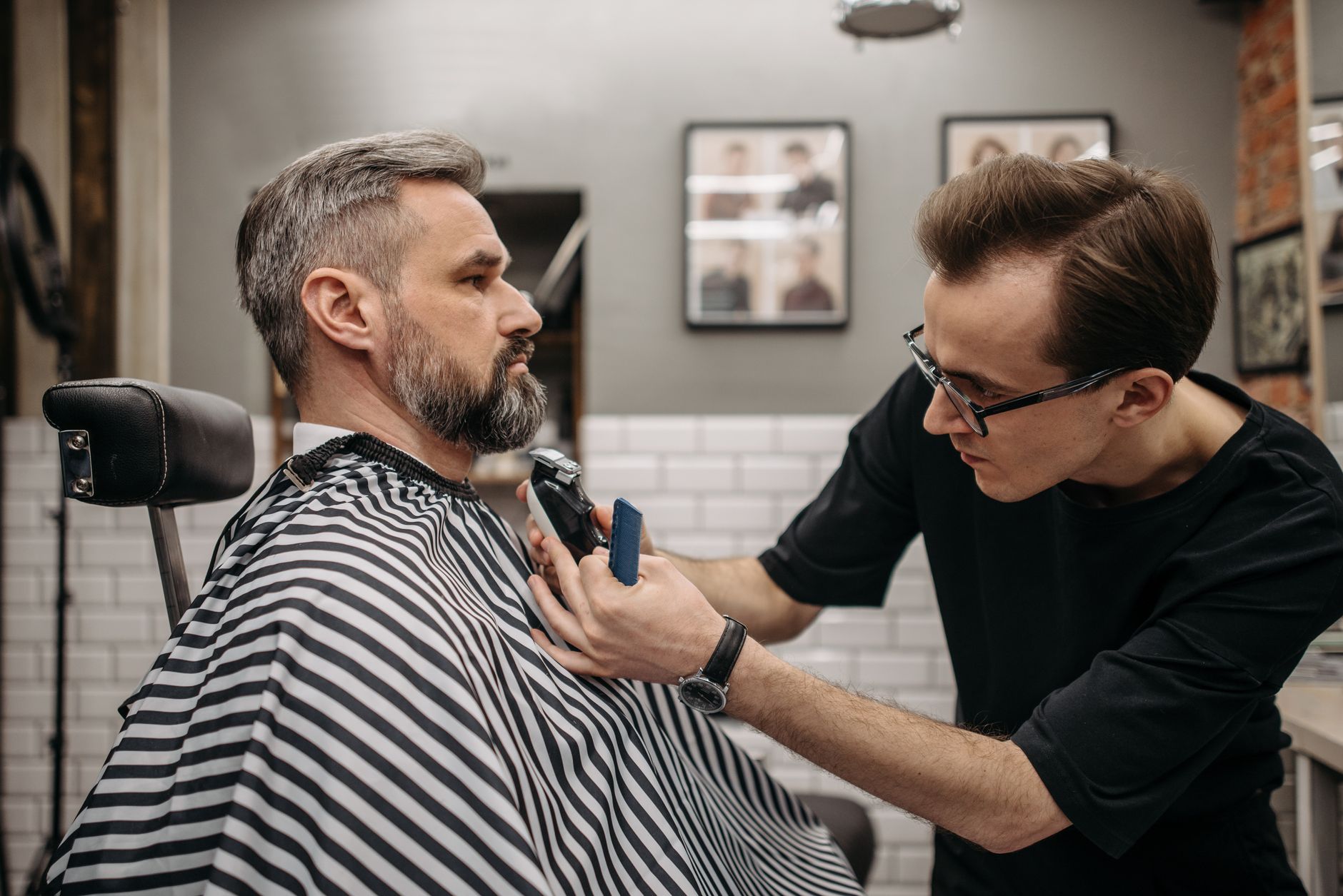 A professional barber precisely trimming a client's beard in a modern barbershop.