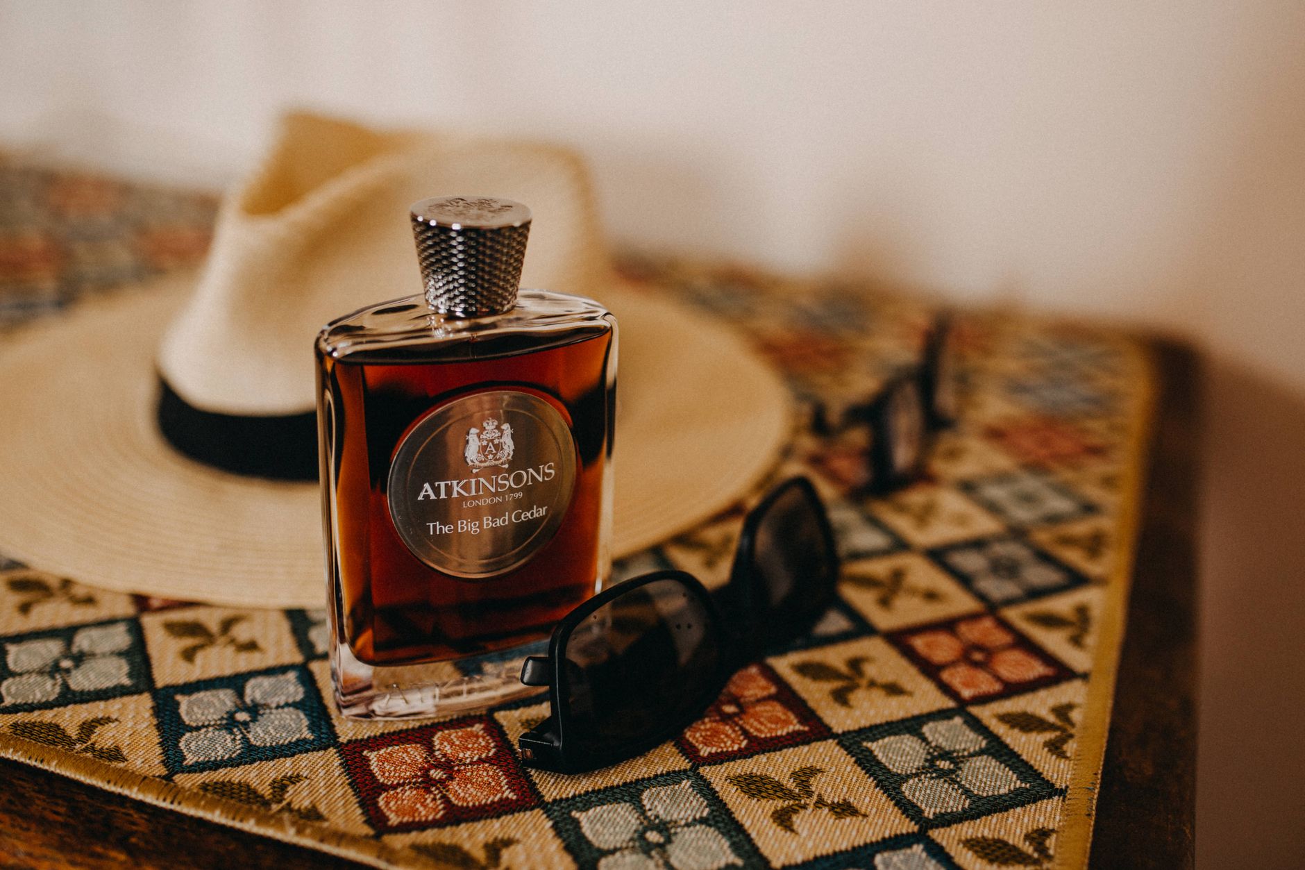 Stylish arrangement of a perfume bottle, fedora hat, and sunglasses on a decorated table.