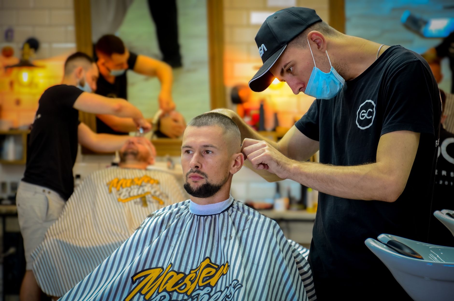 Male barber expertly cutting man's hair in a contemporary barber shop.