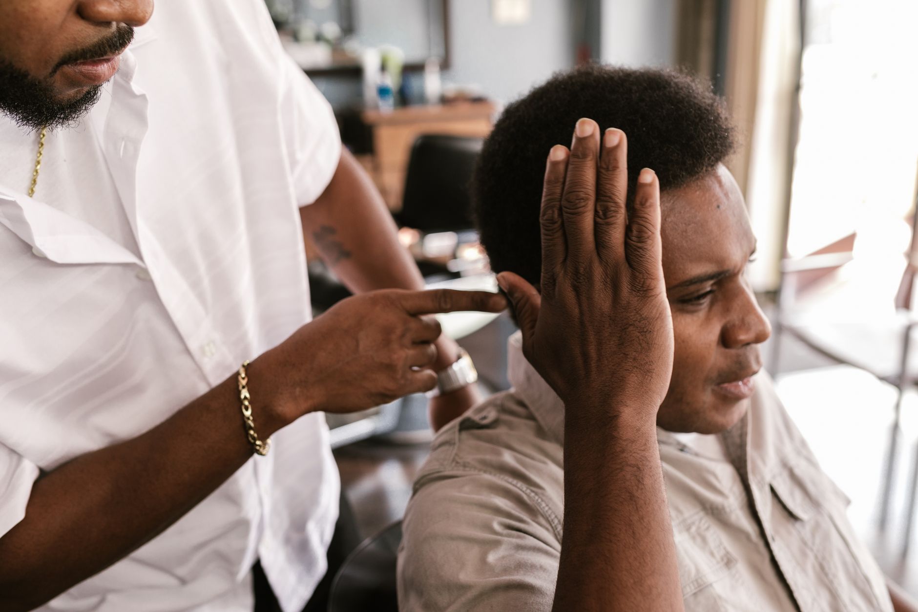 A barber carefully touches up a client's hairstyle in a modern salon setting, creating the perfect look.