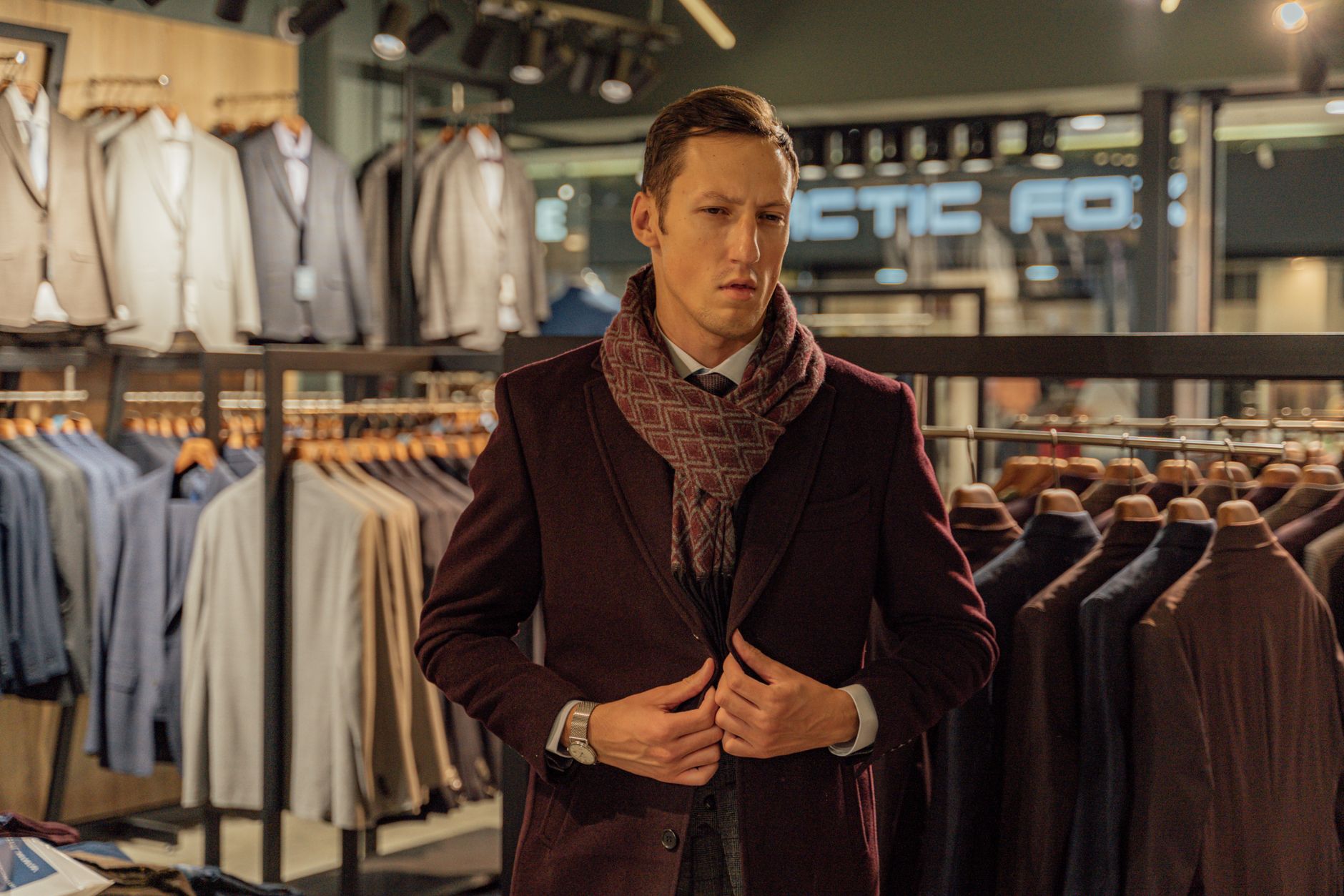 A stylish man in a high-end menswear boutique choosing a coat.