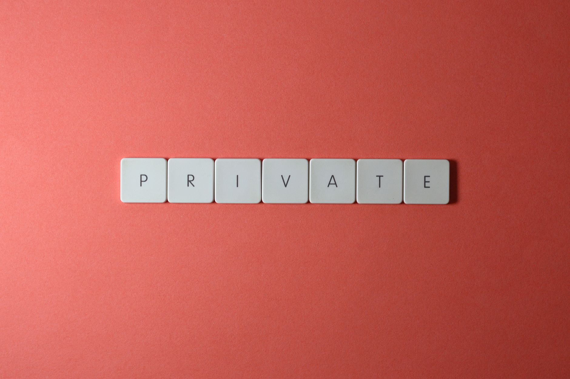 White letter tiles spelling 'PRIVATE' on a red background, offering conceptual minimalist design.