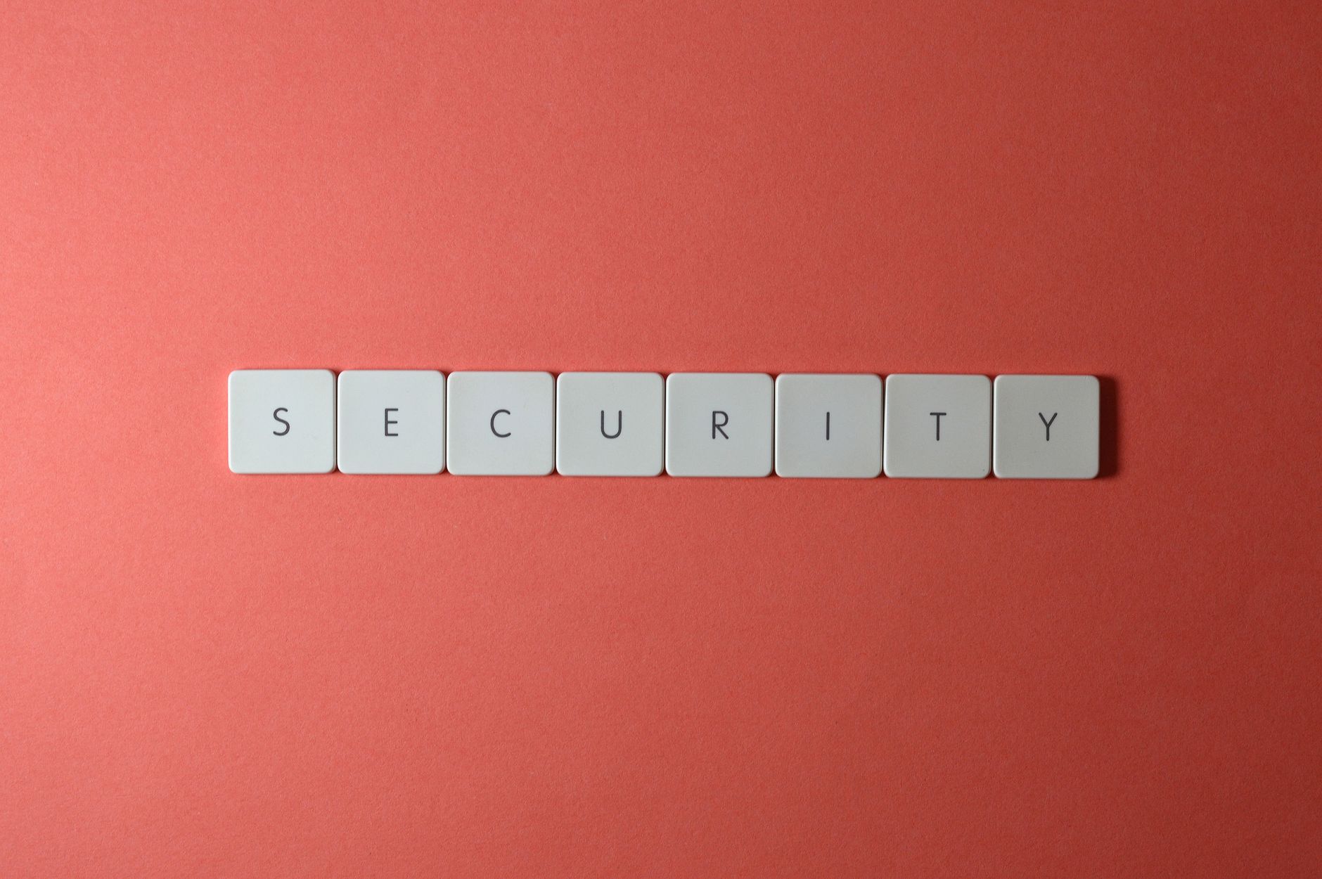 A conceptual image of the word 'security' spelled with keyboard keys on a red surface, providing copy space.