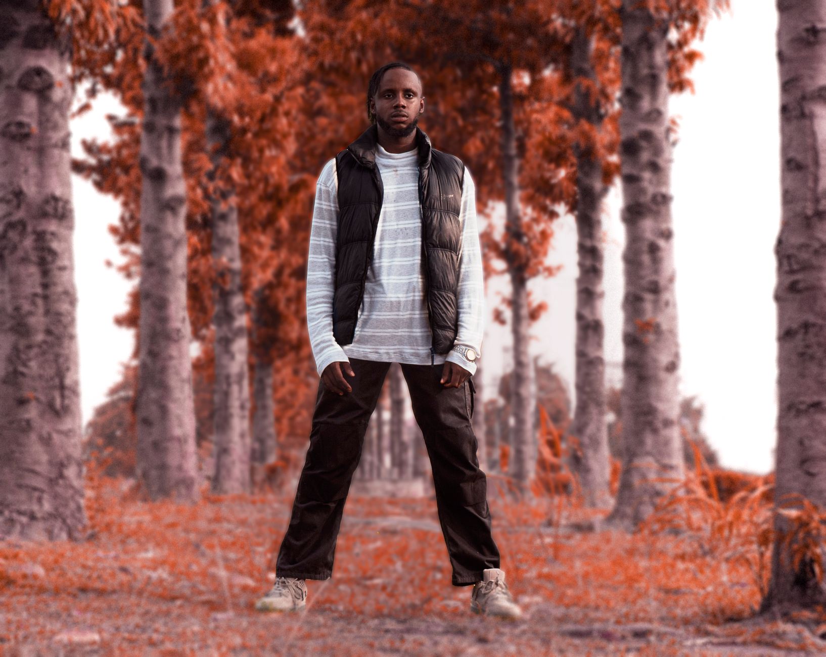 Fashionable man in a vest standing confidently among autumn trees.