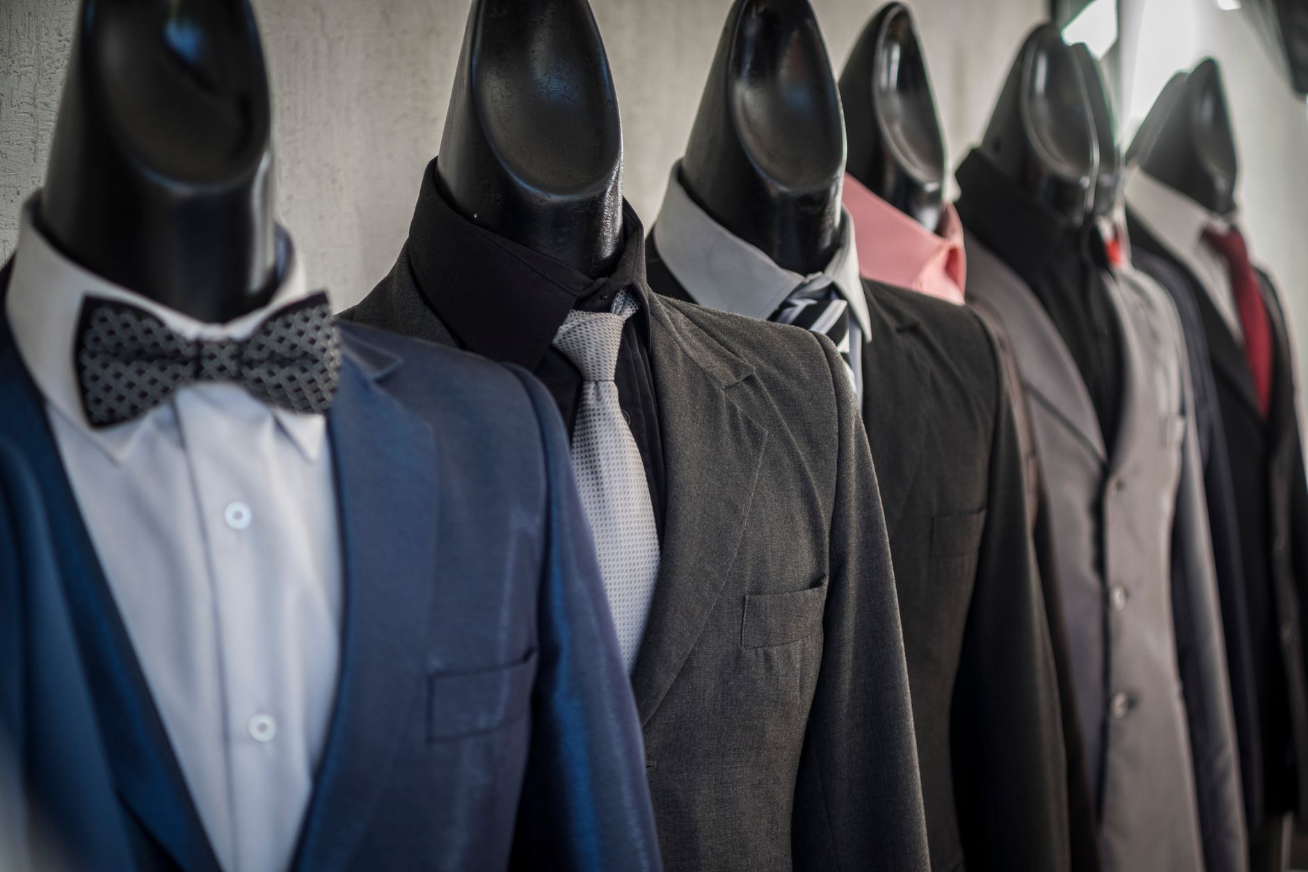 Close-up of mannequins adorned in elegant men's suits in a store setting, showcasing diverse styles.