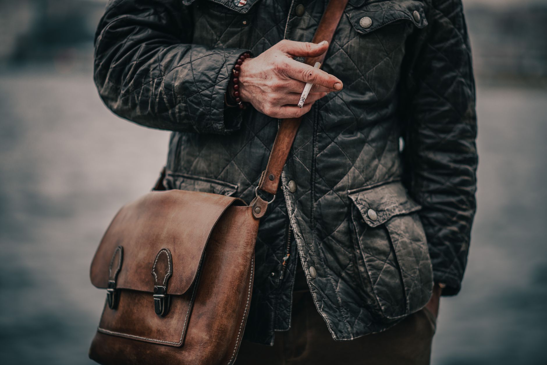 Close-up of a man holding a cigarette and bag by the water in Istanbul.
