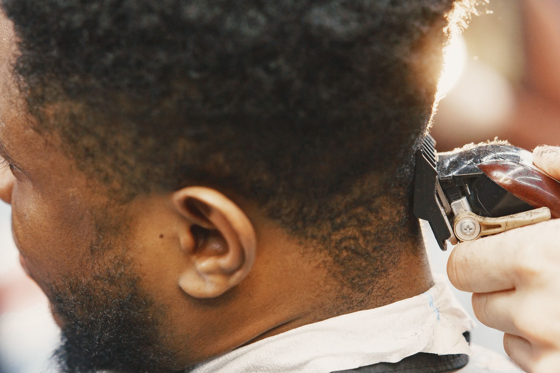 Detailed view of a barber using clippers to trim a man's hair, capturing the essence of grooming.